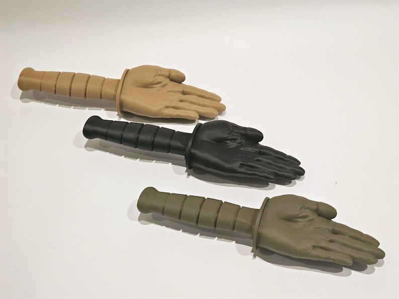 May include: Three training knives with different colored handles and hand-shaped blades. The handles are black, tan, and green.