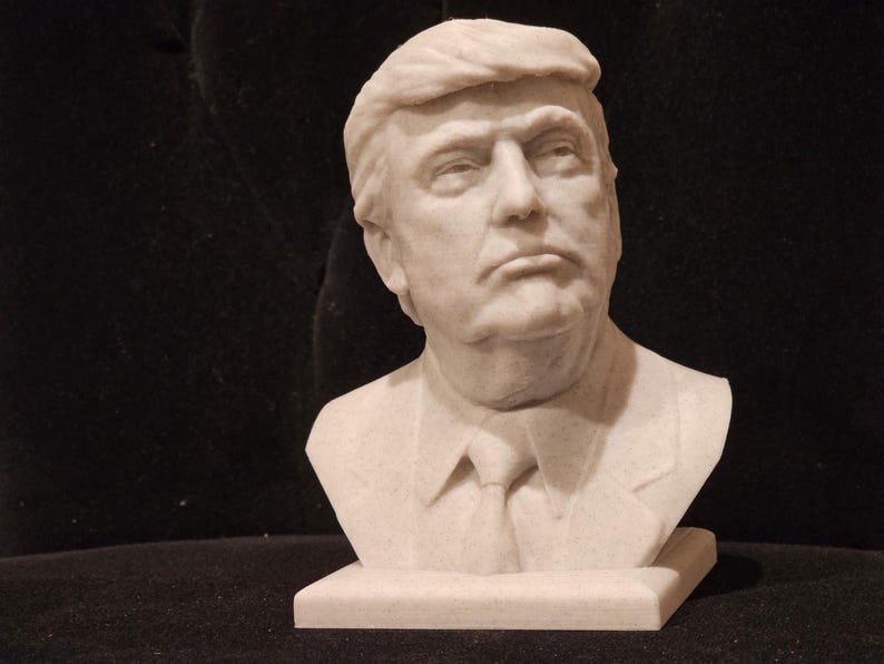 May include: A white marble bust sculpture of a man with short, wavy hair. The bust is on a white marble base.