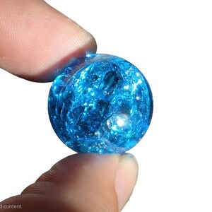 May include: A spherical glass marble featuring a vibrant blue colour with an internal crackled texture. The surface is smooth and reflective, catching light to highlight the intricate network of fractures within the transparent blue material.