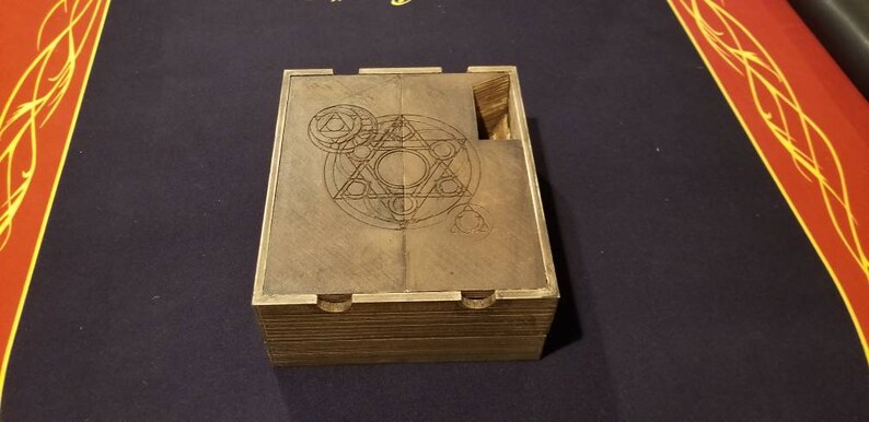 May include: A wooden box with a hinged lid. The lid has an intricate geometric design etched into the wood. The box is closed.