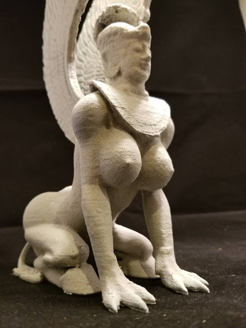 May include: White 3D printed figurine of a woman with wings, a crown, and a necklace. She is kneeling with her hands on the ground.