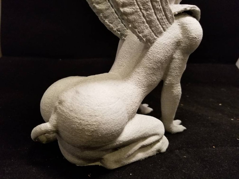 May include: A white, detailed, gargoyle statue with wings, sitting on its haunches. The statue is made of a textured material and has a realistic appearance.
