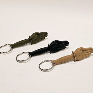 May include: Three keychains with a hand-shaped design. The keychains are green, black, and tan. Each keychain has a metal ring.