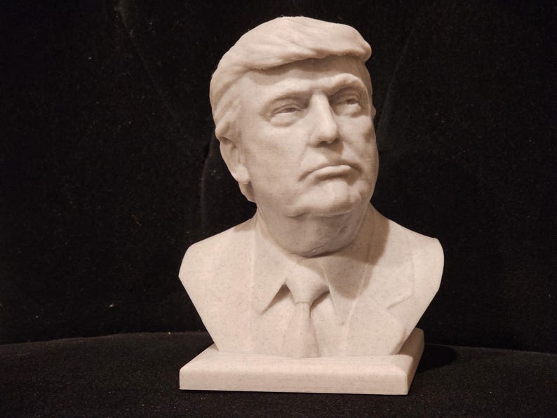May include: A white marble bust sculpture of a person with short, combed-back hair. The sculpture is on a white marble base.