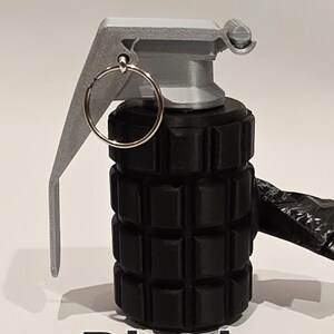 May include: A black novelty grenade with a silver-colored lever and pin. The body of the grenade is cylindrical with a textured surface. The word "Black" is printed in white at the bottom of the image.
