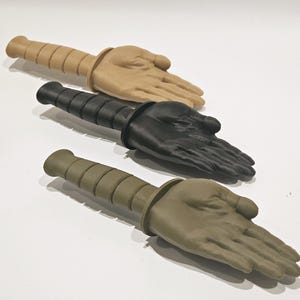 May include: Three training knives with different colored handles. The handles are made to look like a hand. The knives are beige, black, and green.