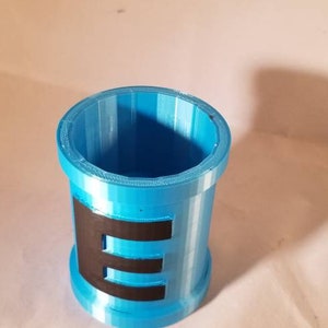 May include: A blue plastic cup with a black letter "E" printed on the side.