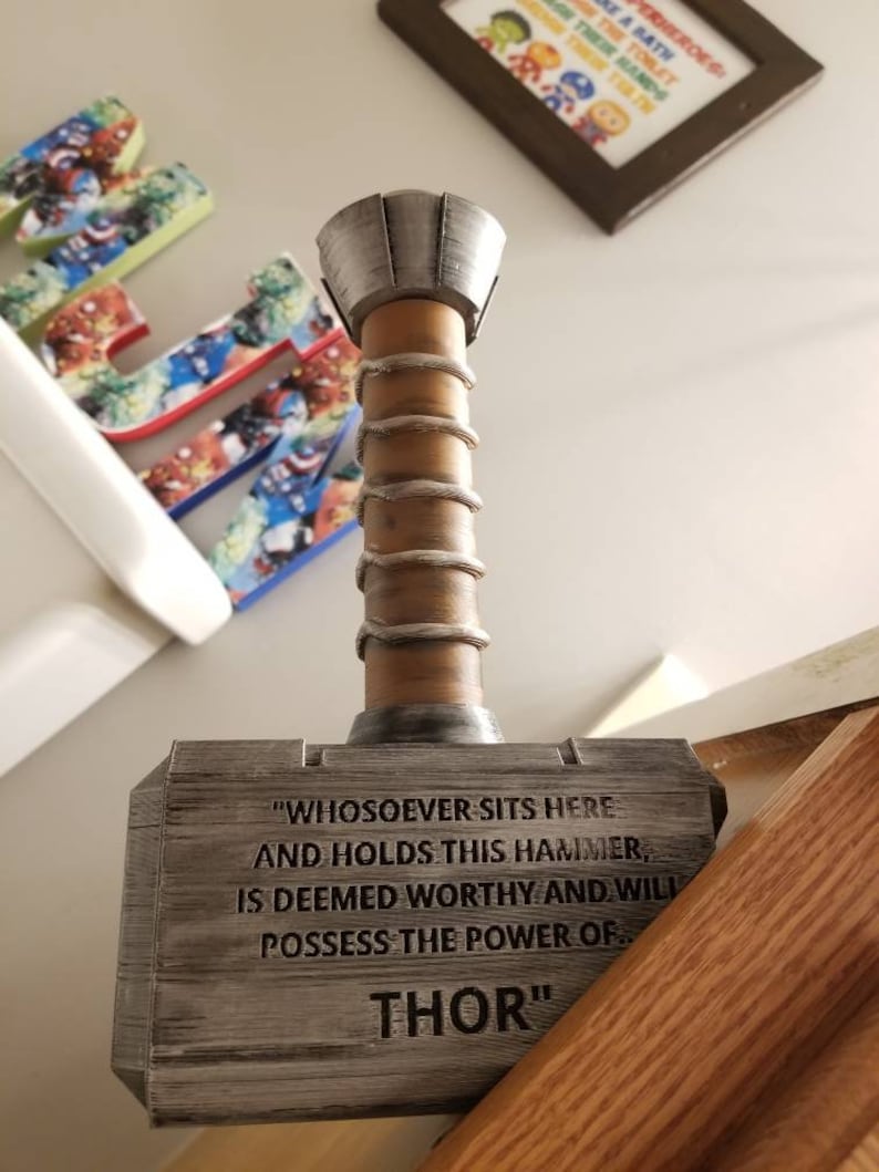 May include: A wooden replica of Thor's hammer, Mjolnir, with a silver metal top. The hammer has a quote engraved on the side: "Whosoever sits here and holds this hammer, is deemed worthy and will possess the power of Thor."