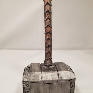 Op de afbeelding: Een zilverkleurige Mjolnir-hamer met een bruine houten handvat. De hamer is een replica van het wapen dat door de Noorse god Thor werd gezwaaid.