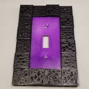 May include: A decorative light switch cover with a purple center and a textured black border. The cover has a single switch opening and two screw holes. The border is made of small, square-shaped blocks.