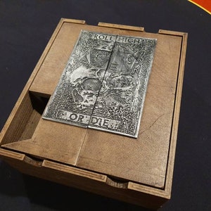 May include: A wooden box with a metal plate on the top. The plate has an engraved design with the words "Roll High or Die".