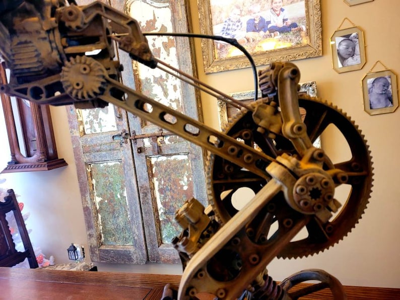 Puede incluir: Primer plano de una escultura de metal de estilo steampunk con engranajes y pi&ntilde;ones. La escultura est&aacute; pintada en un color marr&oacute;n oxidado y tiene un acabado desgastado. La escultura est&aacute; hecha de metal y tiene un dise&ntilde;o complejo.