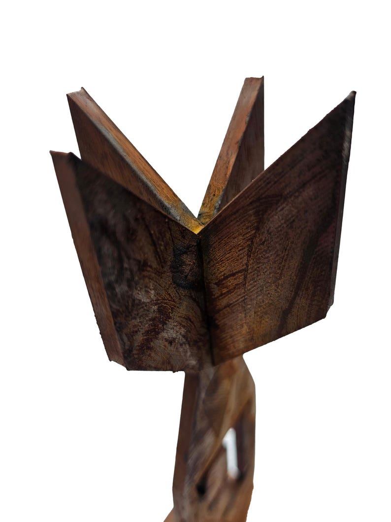 May include: A carved wooden sculpture featuring a starburst design. The sculpture is made of dark brown wood with visible grain and texture. The starburst has five points, and the base is a carved figure.