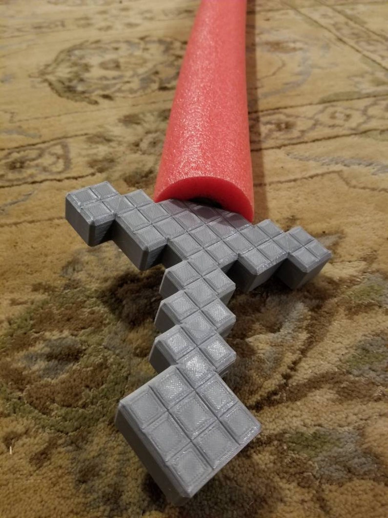 Op de afbeelding: Een grijs 3D-geprint Minecraft-zwaard met een rode schuimrubberen zwembadnoodle-handvat.