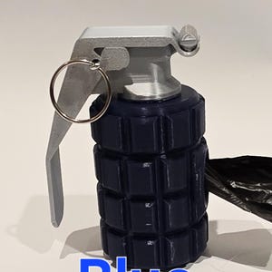 May include: A blue novelty grenade with a silver-colored top and pull ring. The word "Blue" is printed in blue at the bottom of the image. The grenade has a textured body.