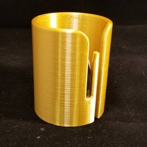 May include: A gold-colored plastic dispenser for wrapping paper or parchment paper. The dispenser has a slot for cutting the paper.