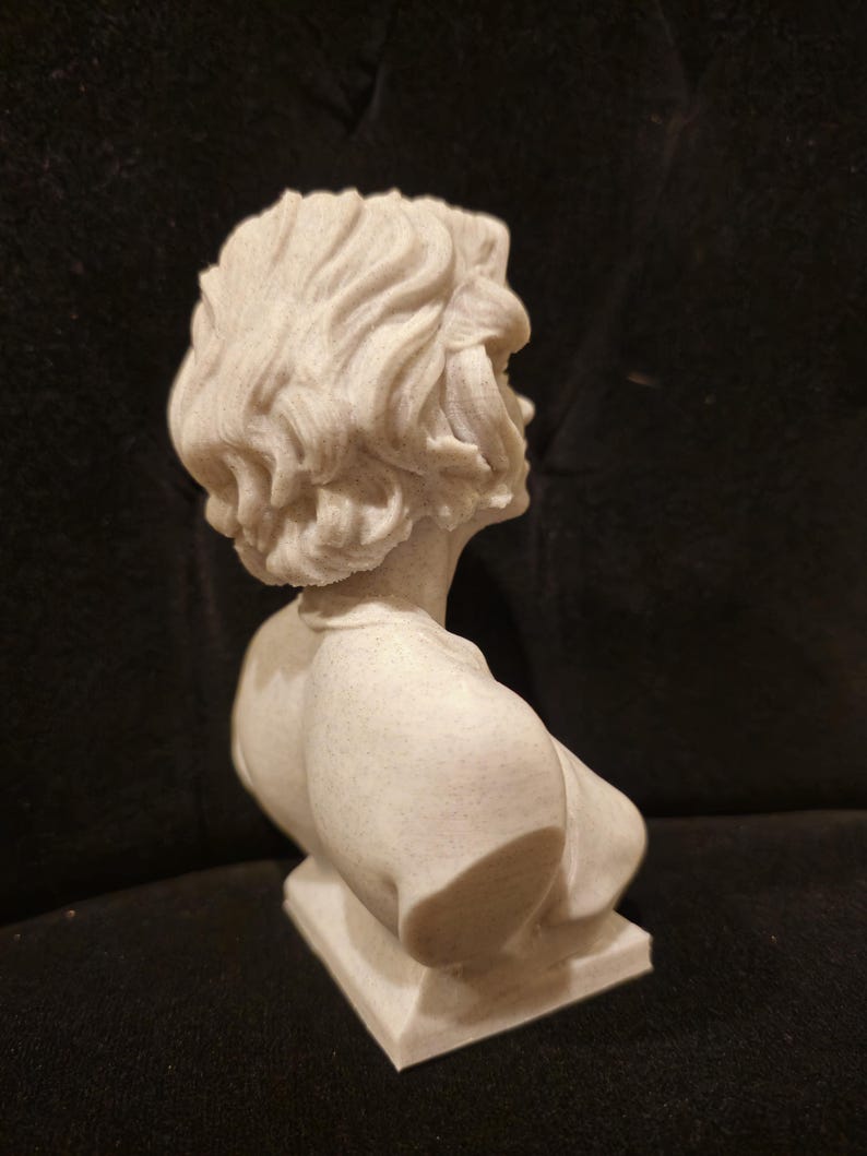 May include: A white bust sculpture of a person with short, wavy hair. The bust is on a square base.