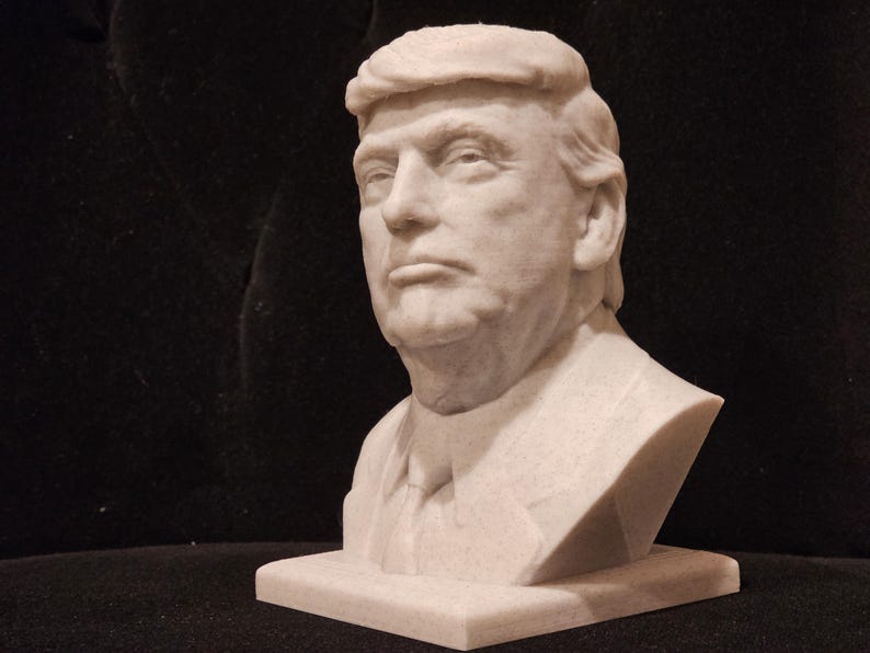 May include: A white bust sculpture of a man with short, combed-over hair. The sculpture is on a white base.