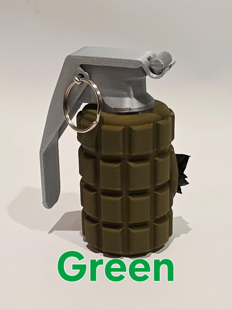 May include: A green grenade with a gray handle and a silver ring. The word "Green" is written in green at the bottom of the image. The grenade has a textured surface.