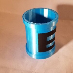 May include: A blue plastic container with a black stripe and the letter "E" printed on it.