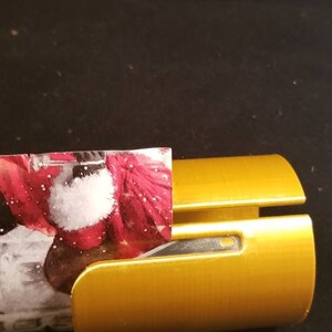 May include: A gold-colored wrapping paper dispenser with a red and white patterned wrapping paper partially inserted.