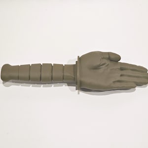 May include: A green plastic hand with a textured handle. The hand is open and palm facing up.