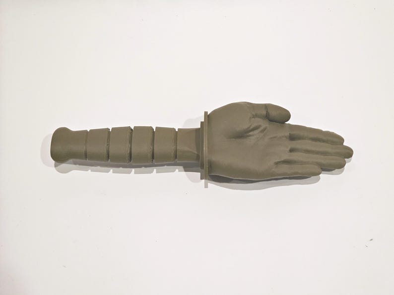 May include: A green plastic hand with a textured handle. The hand is open and palm facing up.