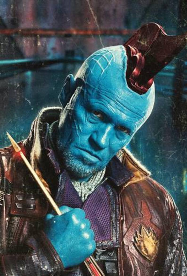 May include: A blue-skinned character with a red mohawk and a brown leather jacket holds a gold-colored weapon. The character has a serious expression on their face.