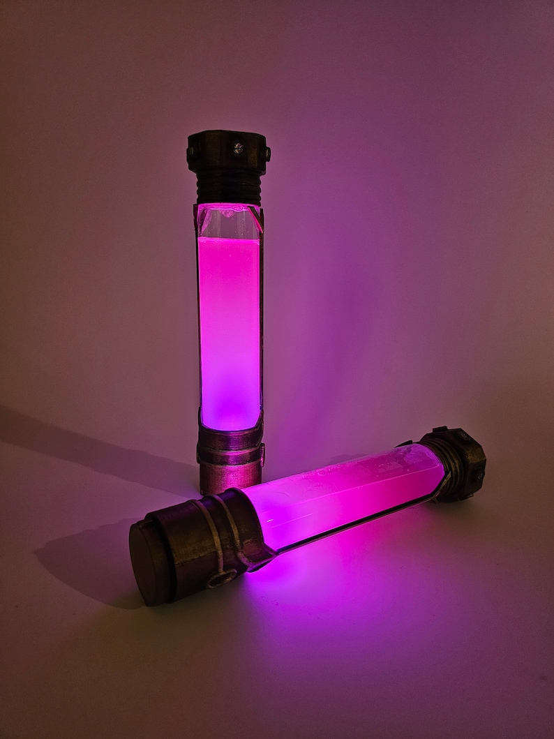 May include: Two glass tubes with a pink liquid inside. The tubes are made of metal and have a decorative design. The tubes are lit from within, giving off a pink glow.