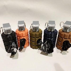 May include: Five dog waste bag dispensers shaped like grenades in black, orange, olive green, navy blue, and brown. Each dispenser has a silver top with a ring and a black bag protruding from the bottom.