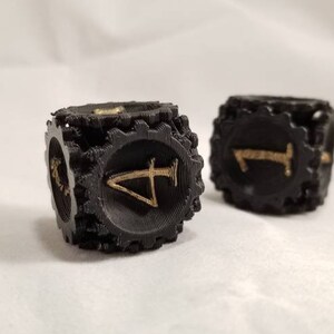 May include: Two black dice with gold numbers. The dice have a gear-like design around the edges.
