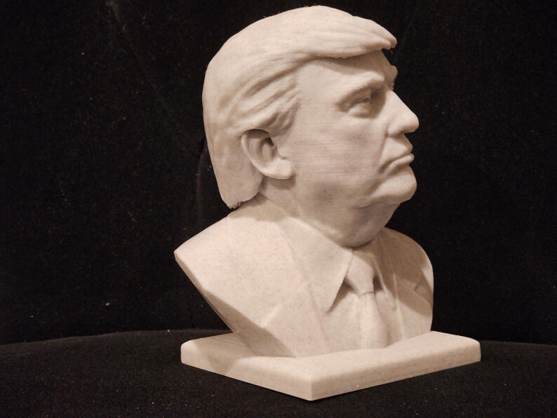 May include: A white bust sculpture of a person with short, styled hair. The sculpture is on a white base.