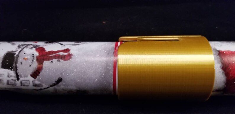 May include: Gold-colored metal wrapping paper holder with a snowman design on the wrapping paper.