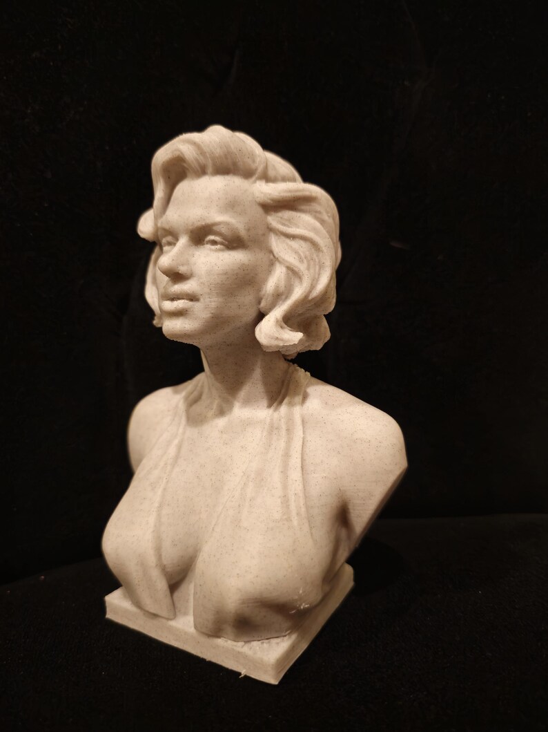 May include: A white bust sculpture of a woman with short, wavy hair. The sculpture is made of a textured material and depicts the woman with a classic, elegant pose.