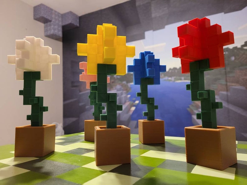 May include: Four colourful block flowers in pots. The flowers are white, yellow, blue, and red. The pots are brown.