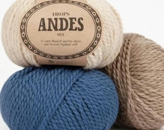May include: Three balls of yarn in beige, light brown, and blue. The beige ball has a label that reads "DROPS ANDES MIX. A warm blend of superfine alpaca and Peruvian Highland wool."