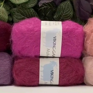 May include: Six skeins of mohair yarn in various shades of pink and purple. The yarn is labeled "Viking Garn Mohair".