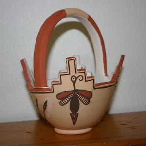 May include: A small, hand-painted ceramic basket with a brown handle and a stylized butterfly design in shades of brown, white, and black.
