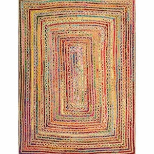 May include: A rectangular braided jute rug with a multi-colored design. The rug features a series of nested rectangles in shades of yellow, red, green, and blue. The rug's texture is visible, with each strand of jute creating a textured surface.