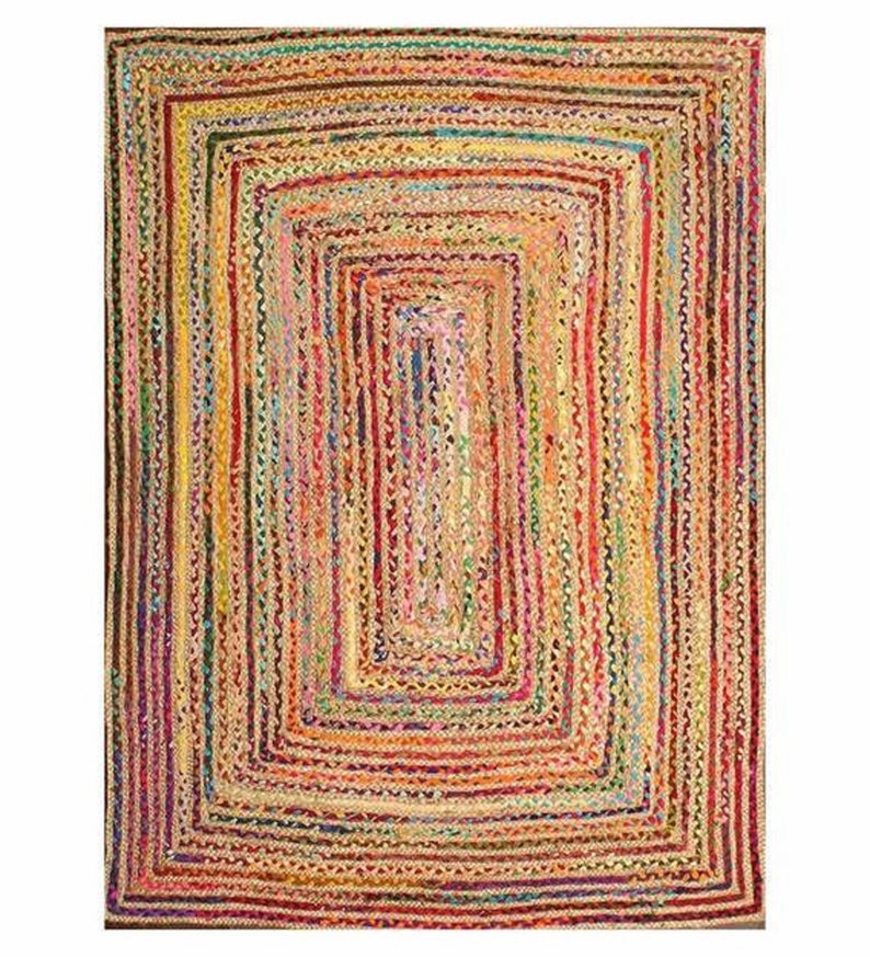 May include: A rectangular braided jute rug with a multi-colored design. The rug features a series of nested rectangles in shades of yellow, red, green, and blue. The rug's texture is visible, with each strand of jute creating a textured surface.