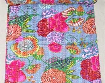 Könnte beinhalten: Eine hellblaue, floral gemusterte Steppdecke mit einem aufgerollten Abschnitt. Die Steppdecke zeigt große, farbenfrohe Blumen in Rosa-, Orange- und Gelbtönen mit grünen Blättern und Akzenten. Die Steppdecke ist mit rotem Faden handgenäht.