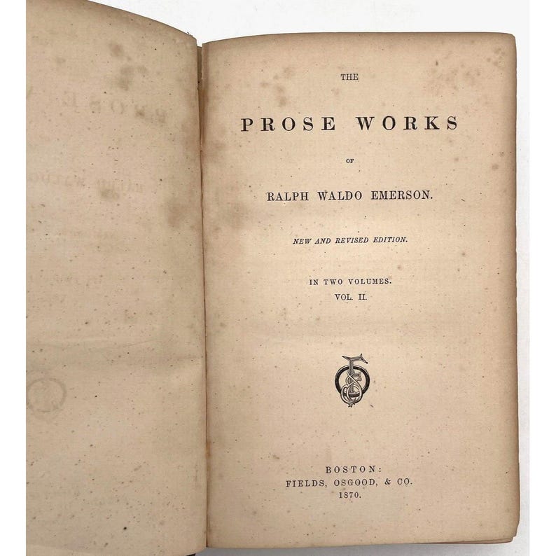May include: An open book with aged, off-white pages. The text reads "THE PROSE WORKS of RALPH WALDO EMERSON. NEW AND REVISED EDITION. IN TWO VOLUMES. VOL. II." Published in Boston by FIELDS, OSGOOD, & CO. in 1870. Includes a decorative emblem.