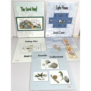 May include: A collection of five art prints featuring coastal themes. Titles include "The Coral Reef," "Light House," "Fishing Flies," "Shells," and "Seaside Collections." Each print showcases detailed illustrations of marine life and coastal elements.