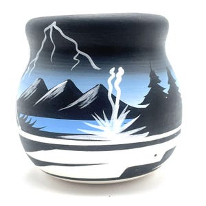 May include: A hand-painted ceramic pot with a landscape design. The pot features a black background with white mountain peaks, a blue lake, and stylized trees. The design includes white lightning and a white plant.