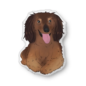 May include: A brown and tan dachshund dog illustration on a white background. The dog has long, floppy ears, a pink tongue, and a happy expression. The illustration is likely a pillow or a decorative item.
