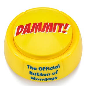 May include: A round yellow plastic button with a large red exclamation mark and the word DAMMIT! printed on the top surface. The side of the button features the blue text The Official Button of Mondays printed in a clear sans-serif font.