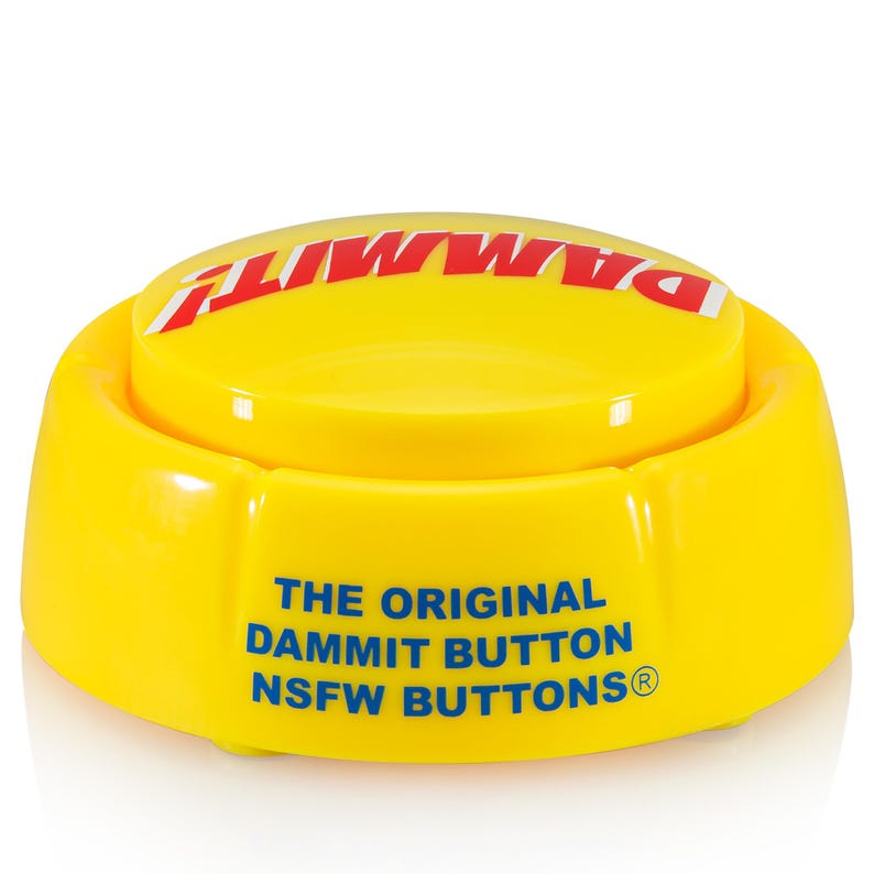 May include: A bright yellow circular plastic button with a flat top and a raised base. The top features the word DAMMIT! in bold red capital letters. The side displays the blue text THE ORIGINAL DAMMIT BUTTON NSFW BUTTONS with a registered trademark symbol.