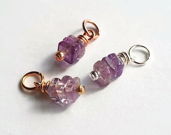 May include: Three jewellery charms featuring faceted, light purple amethyst beads. Two charms are attached to copper-coloured jump rings, while one charm is attached to a silver-coloured jump ring. Each bead is secured with wire wrapping.