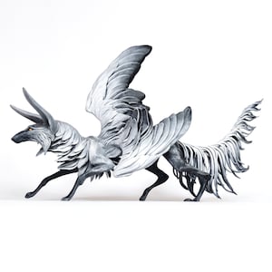 Puede incluir: Una escultura de lobo blanco y gris alado con una cola larga y plumosa. El lobo tiene un hocico largo y un par de cuernos en la cabeza.