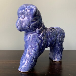 May include: A blue ceramic lamb planter with a textured surface. The lamb is standing on all four legs and has a small opening on its back for planting.